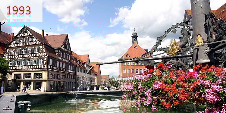 1993 Deutsches Stadtzentrum mit traditionellen Fachwerkhäusern und einem Dorfbrunnen.