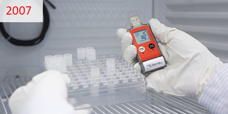 2007 Hände, die einen Temperaturdatenlogger im Kühlschrank halten. 