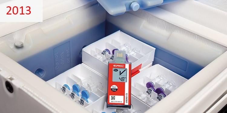 2013 Rotes Überwachungsgerät liegt auf Impfstoffflaschen in einem Kühlbehälter.