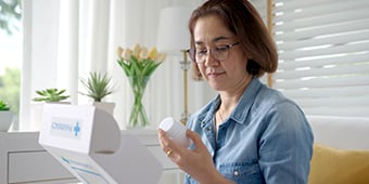 Woman in the living room unpacks medication from a postal package.