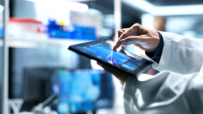 A researcher in the lab operates a tablet held in the palm of his hand.