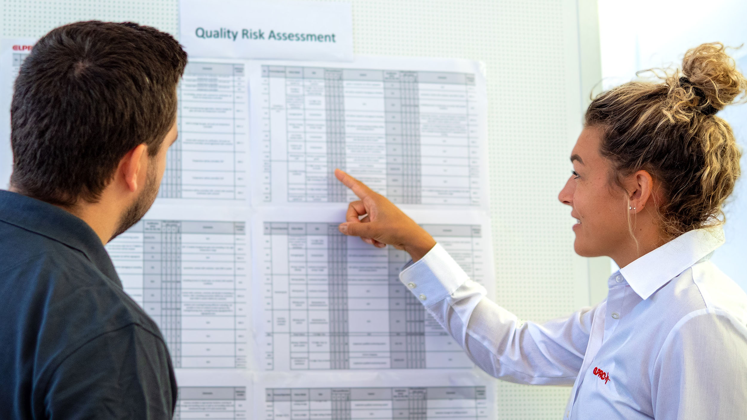 A woman talking to a man about risk management in front of a board