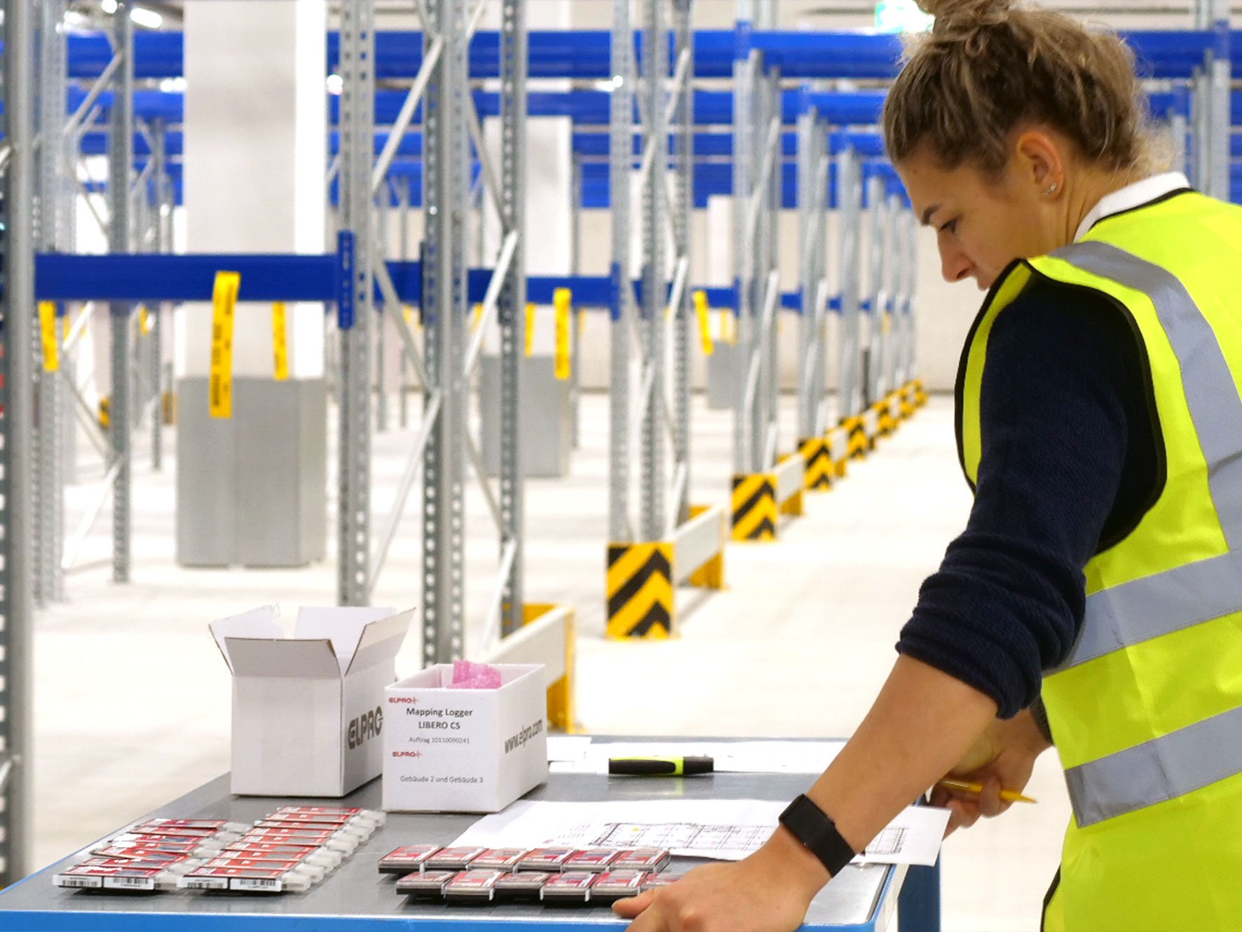 Eine Frau im Lager studiert einen Lageplan auf einem Tischwagen.