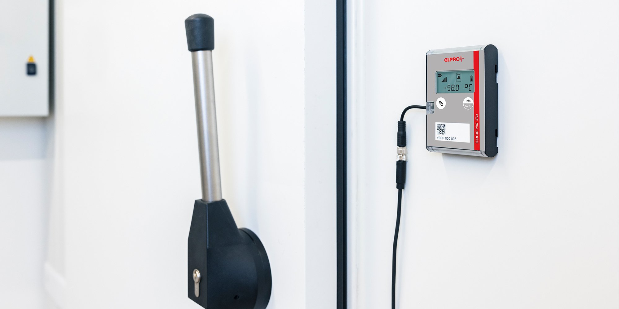 Monitoring device hanging on the door of a freezer room.