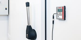 ECOLOG PRO measuring device hangs on a freezer door.