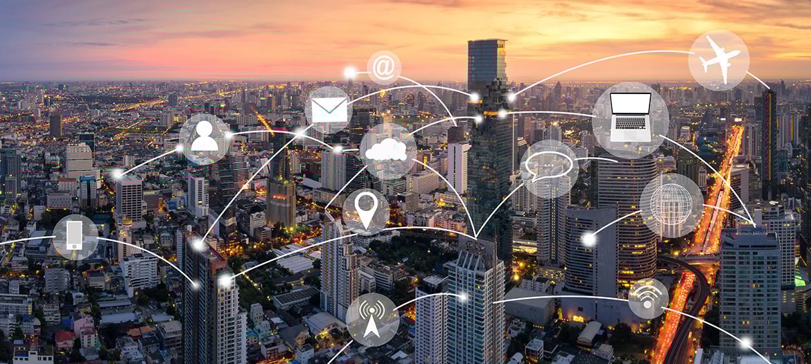 Evening view of a large city in the background, with interconnected icons in the foreground including email, airplane, globe, cloud, and target, representing digital communication and global connectivity.